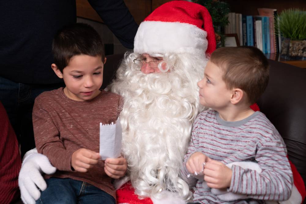 A little boy reading his Christmas list to Santa.